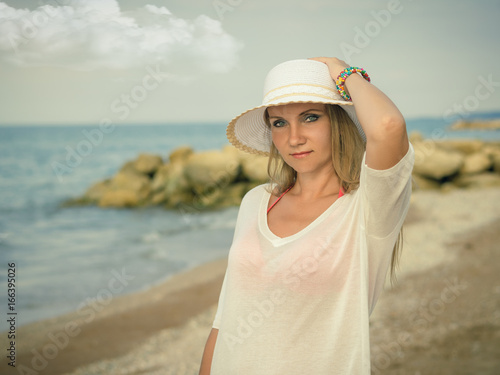 Woman in hat with multi-colored bracelets on the beach. © kvladimirv
