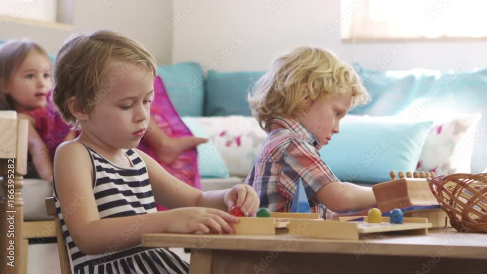 Montessori School Pupils Working At Desk With Wooden Shapes Montessori School Pupils Working At Desk With Wooden Shapes