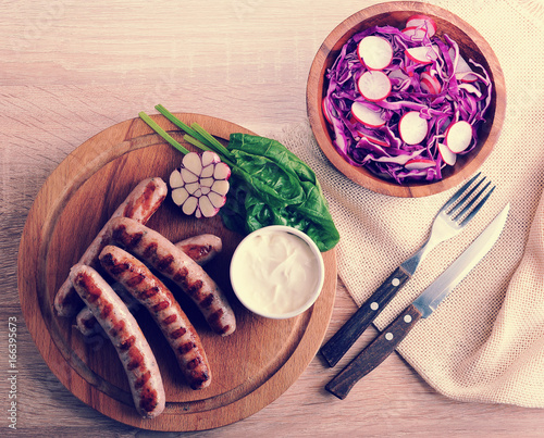 fried sausages on the grill with cream sauce and a salad of radish with red cabbage