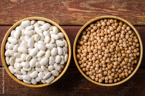 Assorted beans in bowls with chick-pea and kidney bean on wooden background.