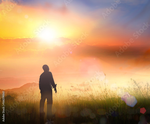 Obraz na plátně Silhouette of man standing on mountain top at sunrise for hope inspiration and C