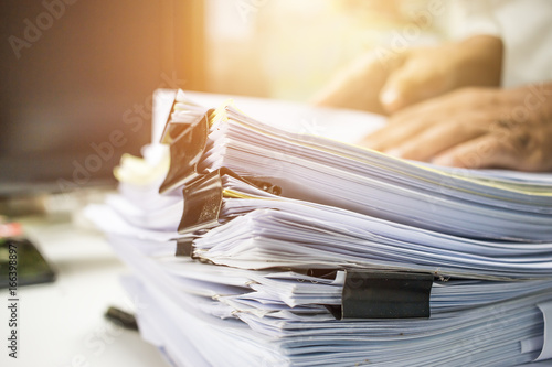 Businessman hands searching information in Stack of papers files on work in office, business report paper or piles of unfinished documents achieves with clips on offices Business concept