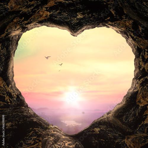 Photography Heart shaped cave opening overlooking a beautiful mountain landscape at sunset o