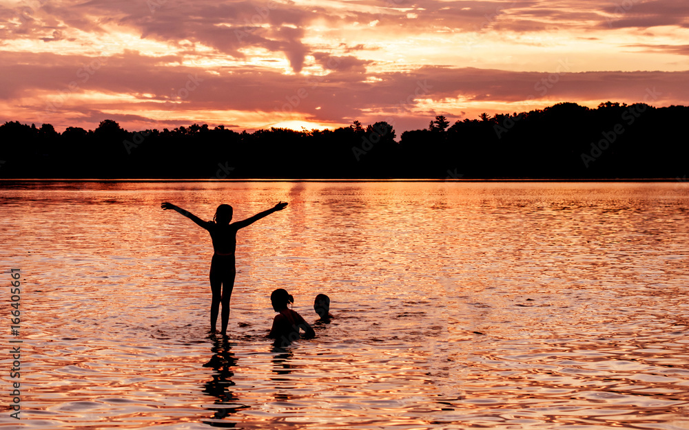 Kids and families are having fun at a lake under sunset	