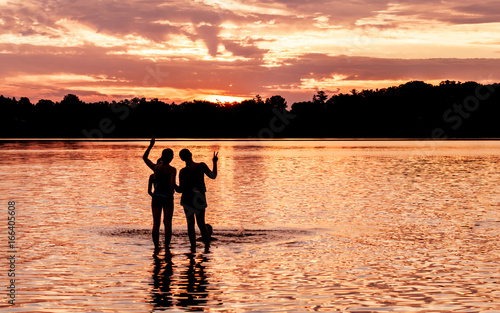 Kids and families are having fun at a lake under sunset 