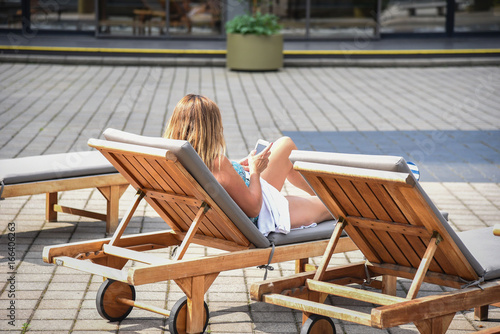 woman looking at her smartphone in deck chair outside in summertime