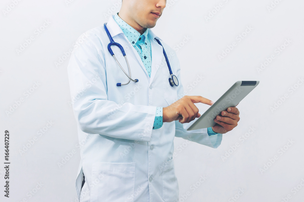 Asian young doctor using digital tablet computer for looking at patient information at clinic, isolated on gray background, concept of medical technology innovation. Asian young doctor using digital tablet computer for looking at patient information at clinic, isolated on gray background, concept of medical technology innovation.