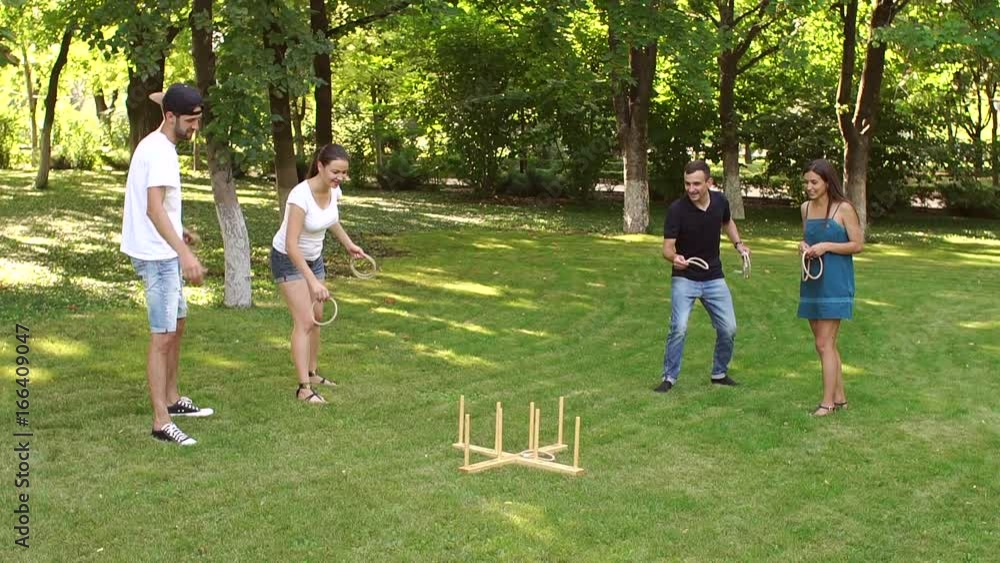 Group of cheerful young friends playing in the active team play ring toss in the Park in the summer. Group of cheerful young friends playing in the active team play ring toss in the Park in the summer.
