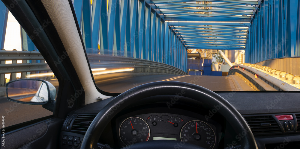 A view of the cockpit of a car driving at night through an illuminated bridge. A view of the cockpit of a car driving at night through an illuminated bridge.