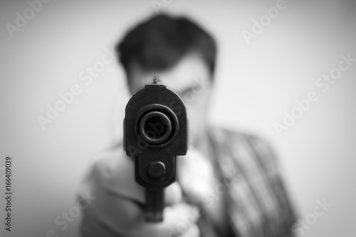 Crazy young man aiming gun at you