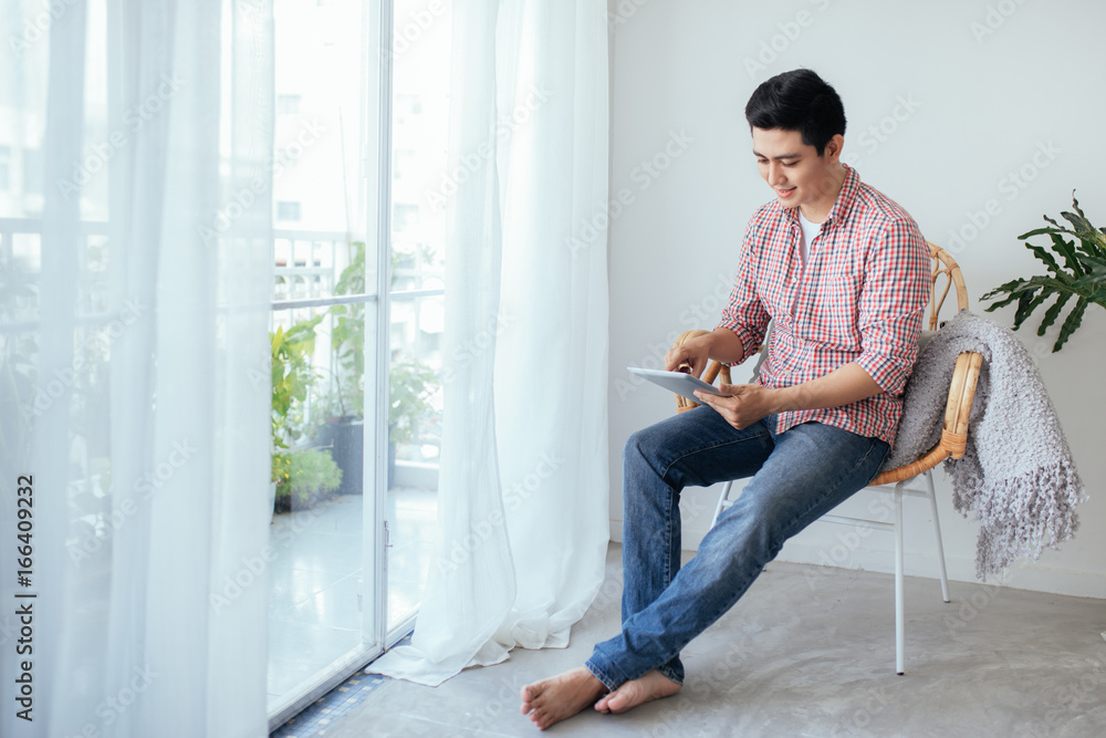 Portrait of a smiling man relaxing on chair near window using table and holding coffee cup. Portrait of a smiling man relaxing on chair near window using table and holding coffee cup.