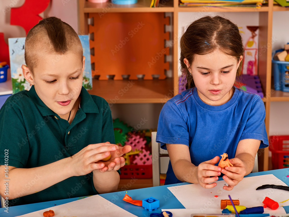 Small students with teacher painting in art school class. Child drawing
