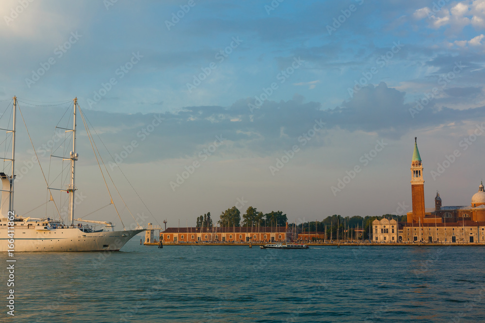 Venice, Italy, July, 2017: Cruise ship passing in front of San Giorgio Maggiore church seen from San Marco square and smaller ships on the Grand canal at sunrise