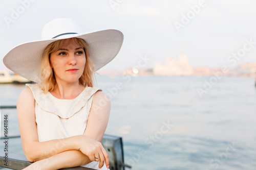 Fashion portrait. Smiling blonde woman in fashionable look. Sea style. On blue background. Style and hot girl outdoor. Woman in straw hat. Fashion. © Angelov