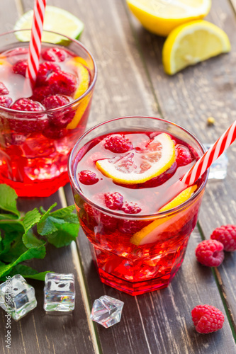 Summer drink with raspberries, lime and ice on a old wooden table