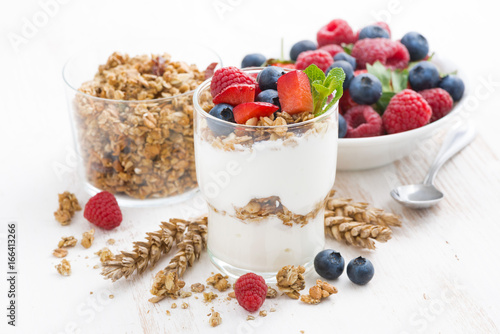 healthy dessert with natural yogurt, muesli and berries on a white table