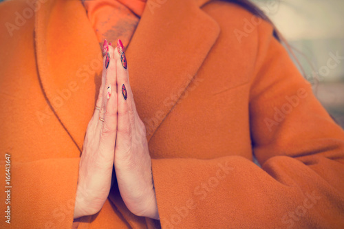 Womans hands in yoga lotus pose in orange dress close up