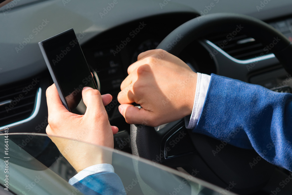 The driver of the car uses the phone while the car is moving, close-up