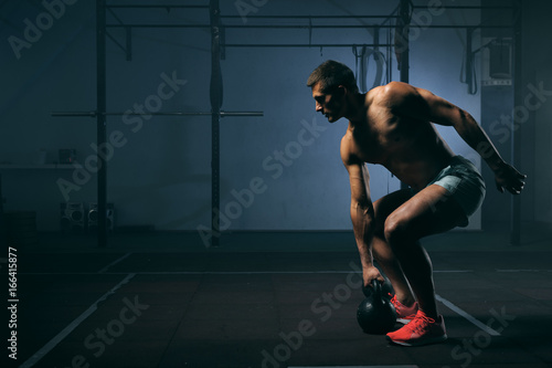 Young man with naked torso working out in gym photo