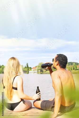 Young couple having a beer by a lake