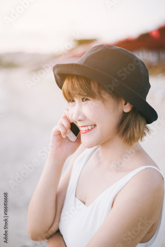 Asian woman use mobile phone on the beach.