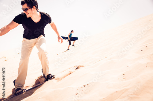 Tourist Sandboarding In The Desert