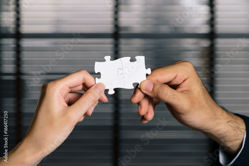 business persons holding pieces of jigsaw puzzle. teamwork concept.