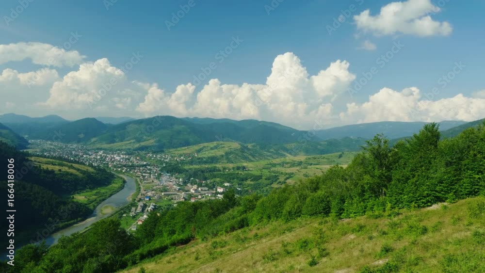 A small village near the river. Against the background of the mountains covered with forest. Ski resort in summer, rest in the mountains. View from the ski lift A small village near the river. Against the background of the mountains covered with forest. Ski resort in summer, rest in the mountains. View from the ski lift