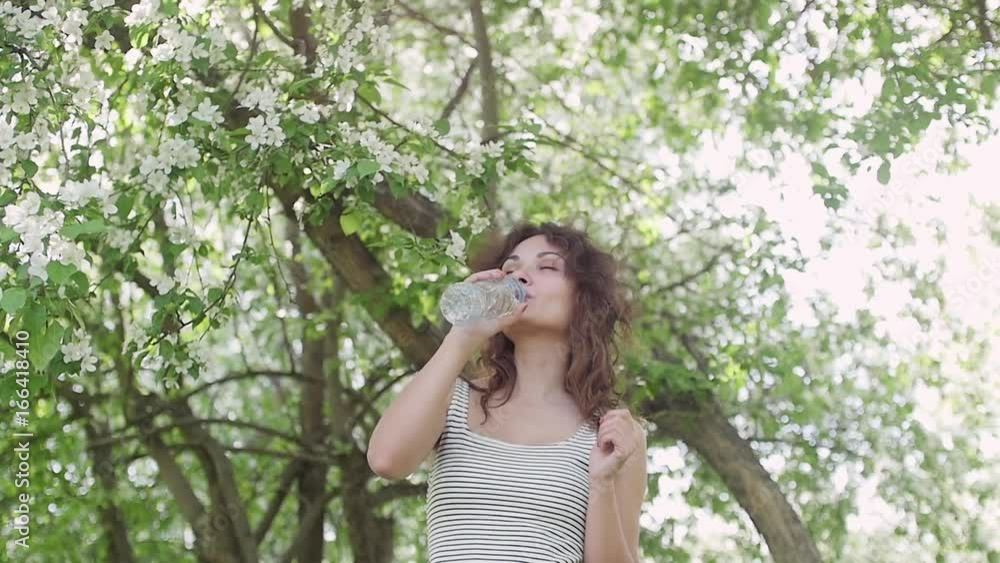 woman in Park drinking water from bottle woman in Park drinking water from bottle