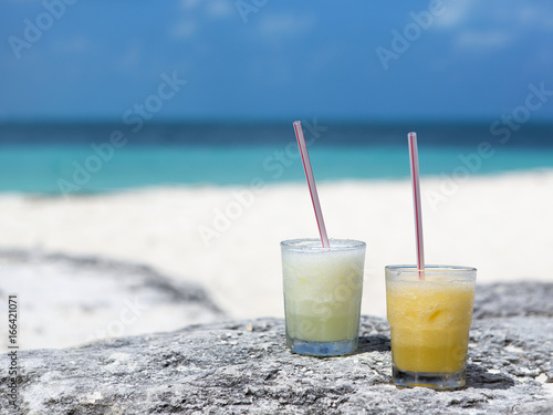 Colorful drink on the beach. Sunny and hot day. Refreshing cold cocktail with a straw. Focus point on the drink.