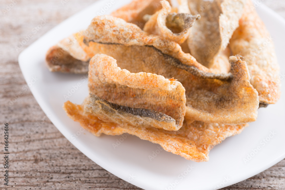 Crispy fried salmon skin on wood background Crispy fried salmon skin on wood background