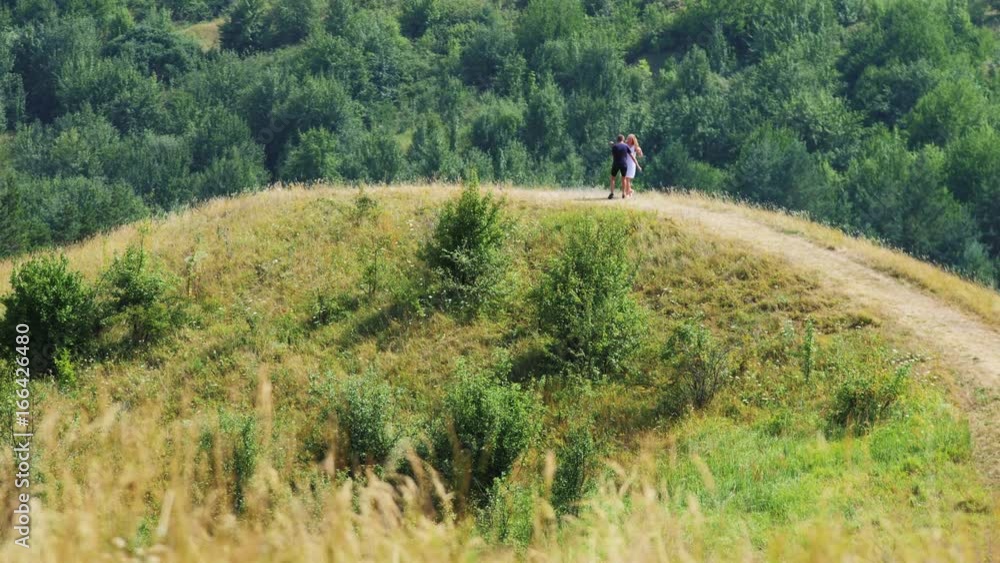 The couple in love are running up the hill, the guy is circling around the girl taking her in his arms. The couple in love are running up the hill, the guy is circling around the girl taking her in his arms.