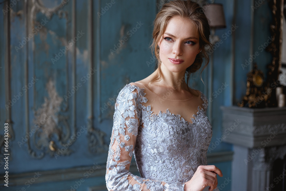 Naklejka premium Young blonde bride woman in a light blue wedding dress, fashion beauty portrait in interior