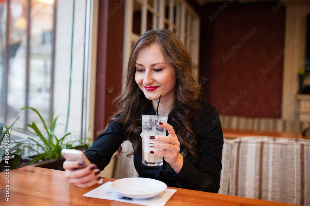 Beautiful girl drinking coffee and looking in the phone Beautiful girl drinking coffee and looking in the phone