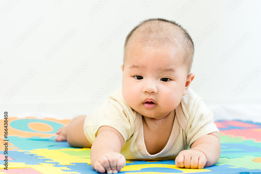 Portrait of a little adorable infant baby girl lying on the tummy on colorful eva foam indoors Portrait of a little adorable infant baby girl lying on the tummy on colorful eva foam indoors