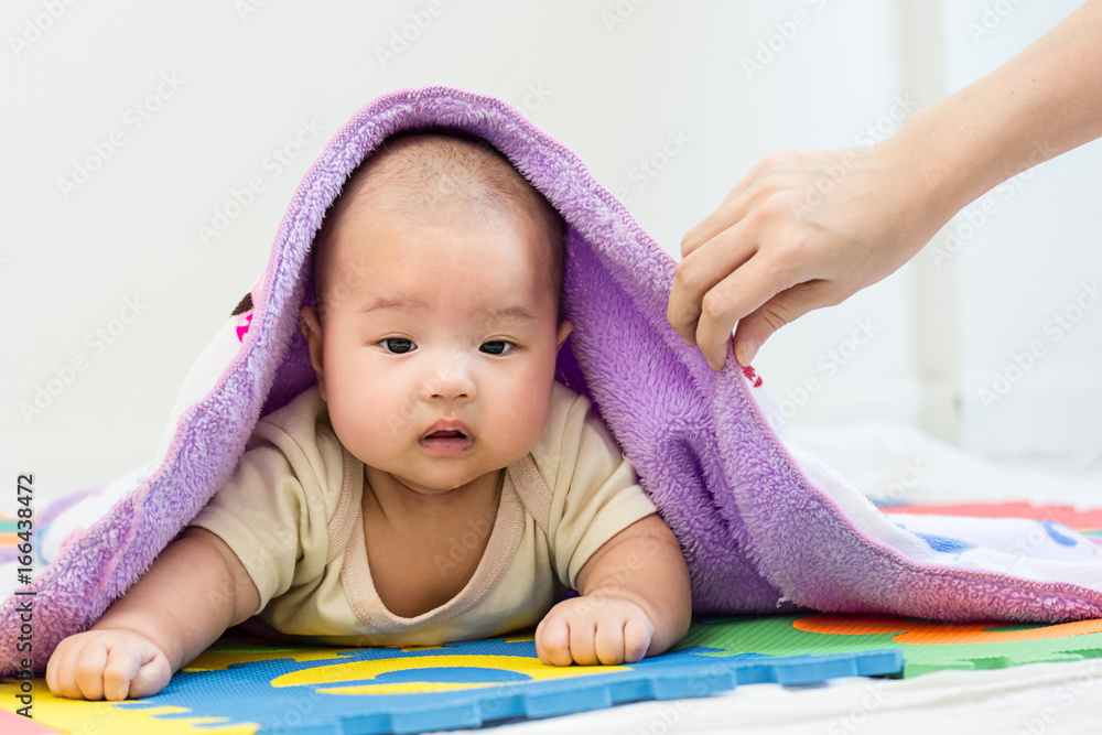 Portrait of a little adorable infant baby girl with blanket lying on the tummy on colorful eva foam indoors Portrait of a little adorable infant baby girl with blanket lying on the tummy on colorful eva foam indoors
