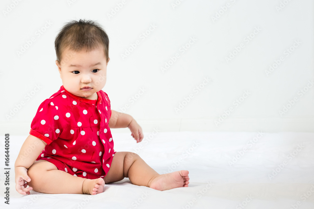Portrait of adorable infant baby girl sitting on the bed with copyspace Portrait of adorable infant baby girl sitting on the bed with copyspace