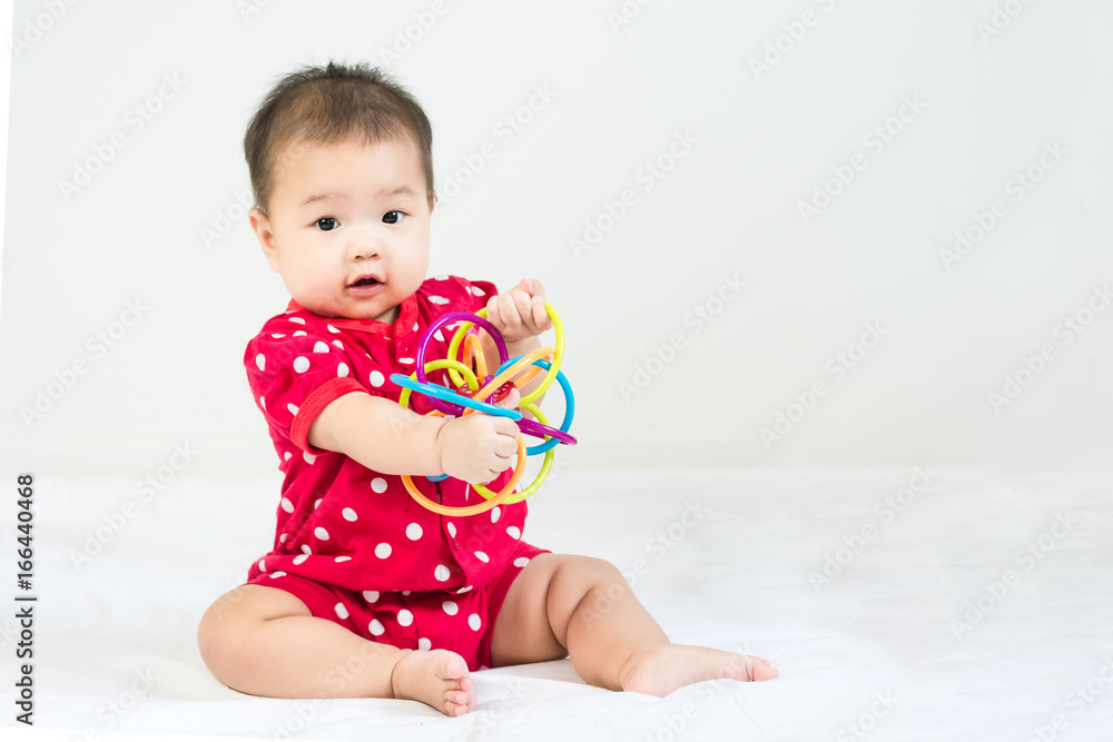 Portrait of adorable infant baby girl sitting on the bed with bites toy Portrait of adorable infant baby girl sitting on the bed with bites toy