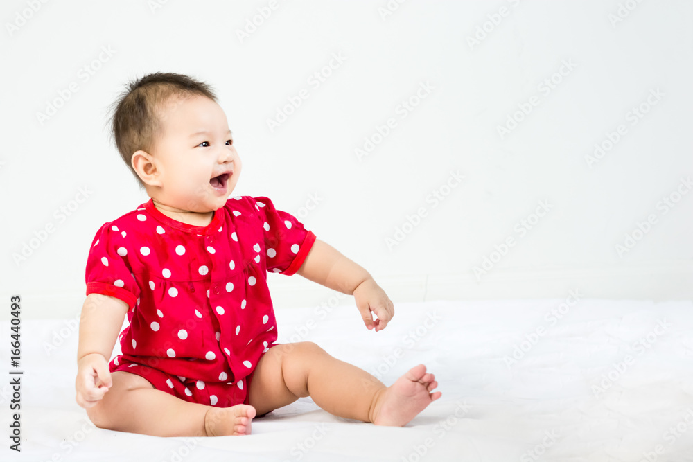 Portrait of adorable infant baby girl sitting on the bed with copyspace Portrait of adorable infant baby girl sitting on the bed with copyspace