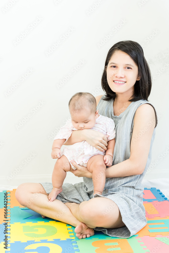 Portrait of happy asian mother hugging her cute little baby and looking in camera indoors Portrait of happy asian mother hugging her cute little baby and looking in camera indoors