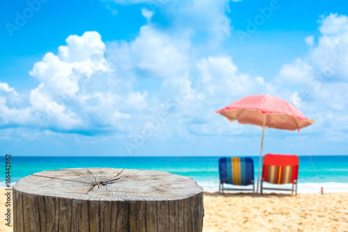 Fototapeta Naklejka Na Ścianę i Meble -  Wooden desk or stump on sand beach in summer,Beach chairs with umbrella  background.