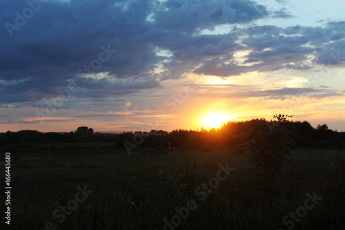 Countryside sunset. Beautifully lit clouds, the silhouette of the village © sorocka