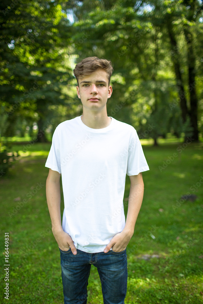 young man in blank white t-shirt: design, people, education concept. nature background young man in blank white t-shirt: design, people, education concept. nature background