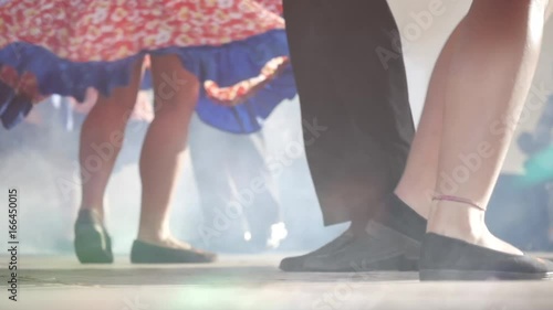 Teenager dancers performing a folklore dance on stage. Detail of legs and feet. Slow motion	