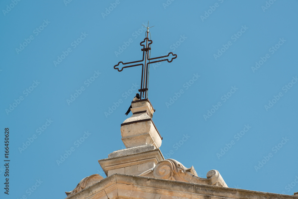 Eine Elster auf dem Kuppelkreuz einer Kirche