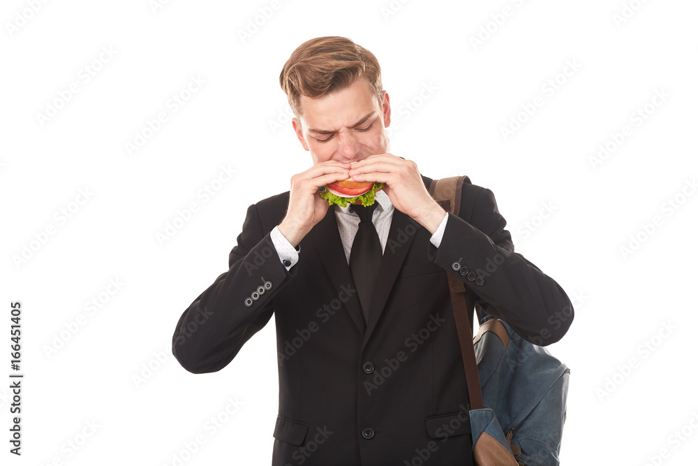 Portrait of college student in black suit eating sandwich against white background Portrait of college student in black suit eating sandwich against white background