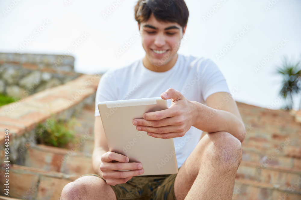 Young happy man sitting on stairs outside using tablet Young happy man sitting on stairs outside using tablet