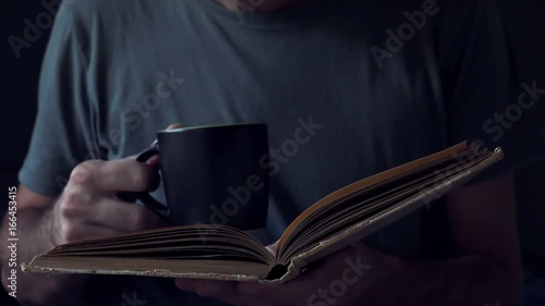 Man reading book and drinking coffee, adult male person enjoying leisure relaxational home weekend activity photo