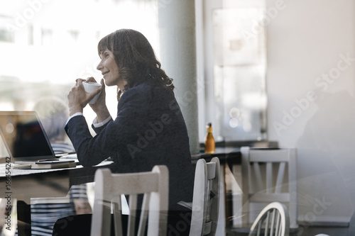 Businesswoman with laptop, sitting in cafe, drinking coffee photo