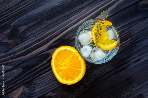 Cut orange near the alcoholic cocktail on dark wood table top view. Blank space for text placement photo